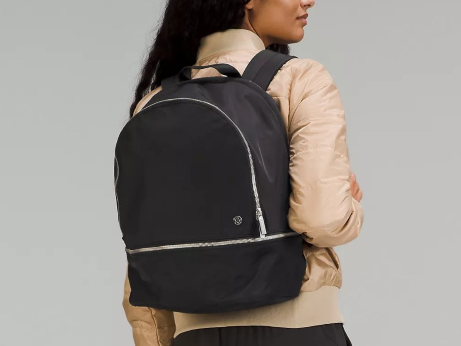 woman wearing a tan top showing her back carrying a black lululemon backpack