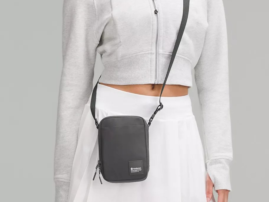 woman waring a white cropped zip hoodie and skirt with a black lululemon Crossbody Bag 