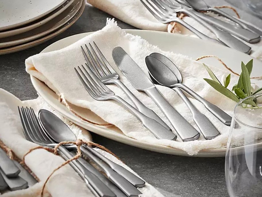 stainless steel flatware set laying on napkins on table