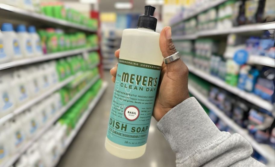 a womans hand holding a bottle of mrs meyers dish soap