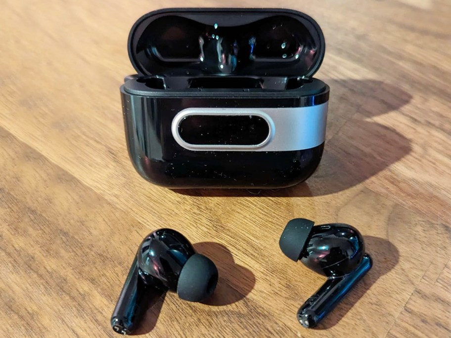 black earbud case with earbuds in front of it on table