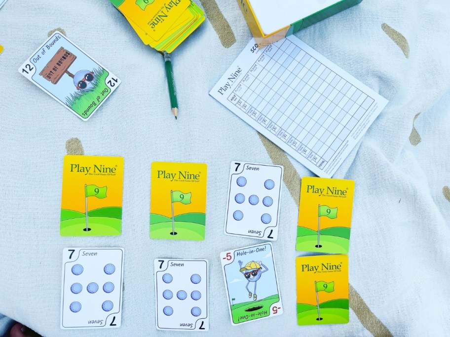 Play Nine Card game cards, score pad and pencil on a blanket outdoors