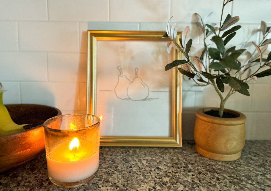 gold frame next to olive plant and candle