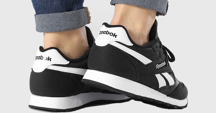 person wearing black and white reebok shoes 