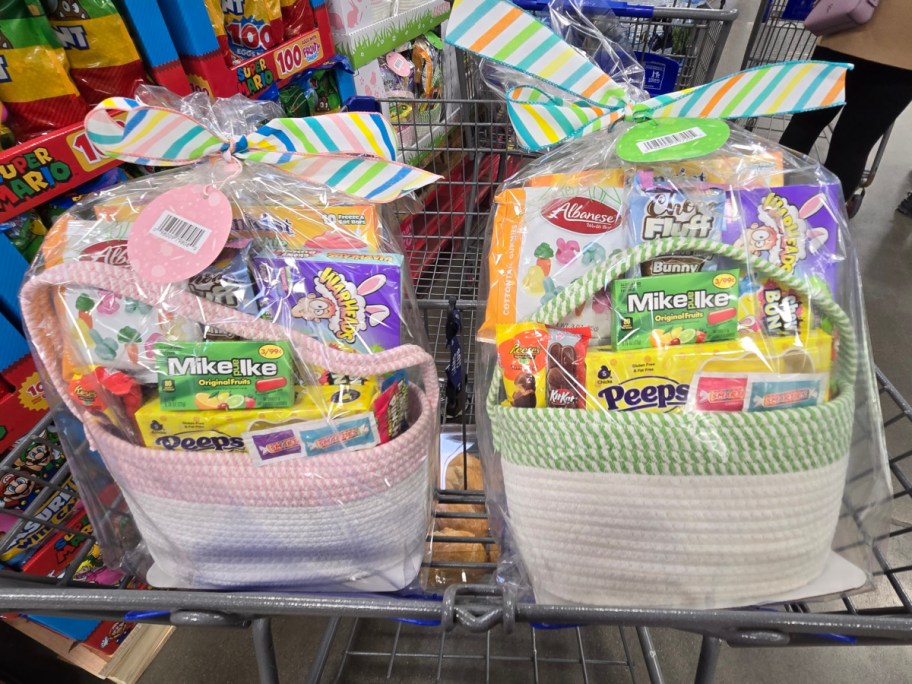 Two colorful Easter baskets filled with candy, wrapped in cellophane, and adorned with striped bows, sit in a shopping cart.