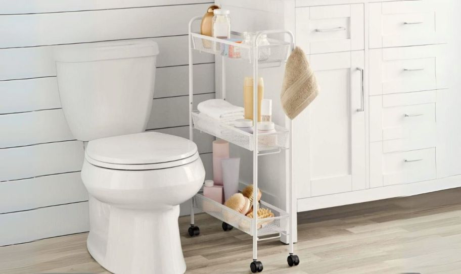slim rolling bathroom organizer cart shown between a toilet and the bathroom vanity