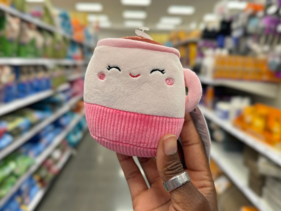 hand holding a latte shaped Squishmallow pet toy