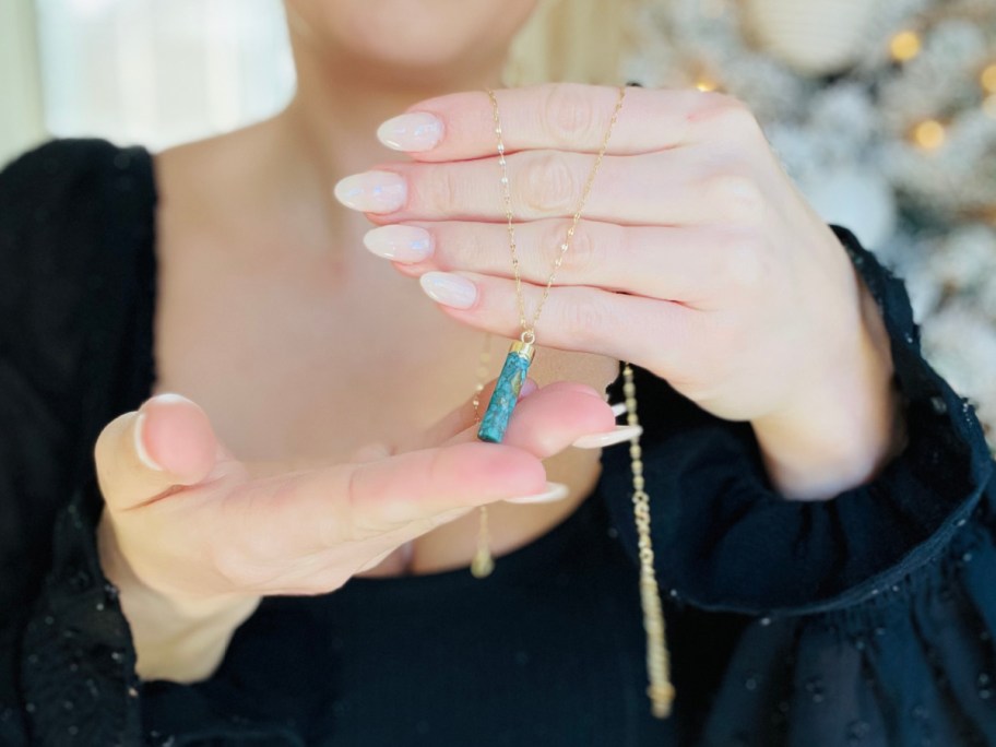 hands holding turquoise pendant necklace