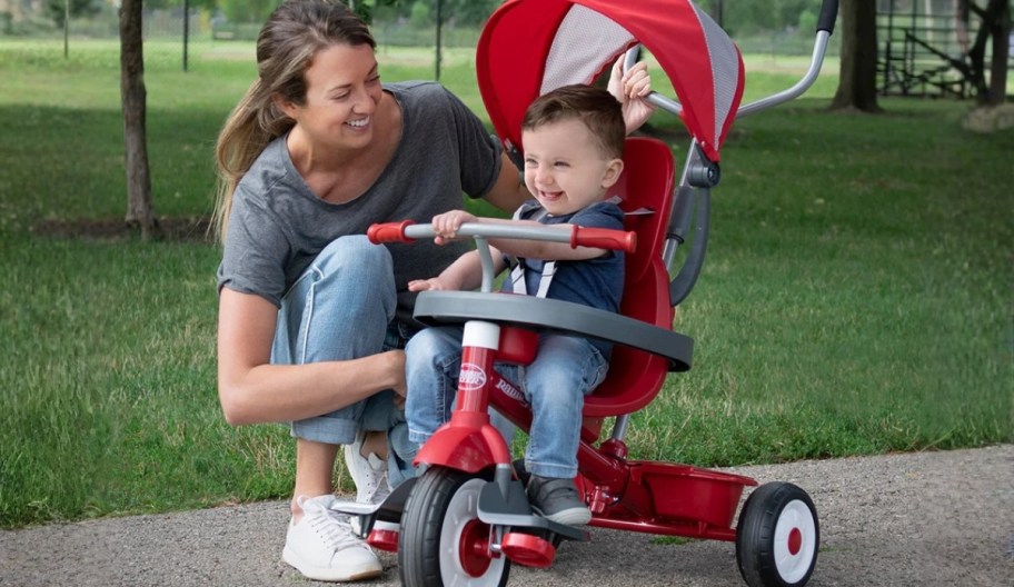 a mom with a kid seated on a stroll n trike