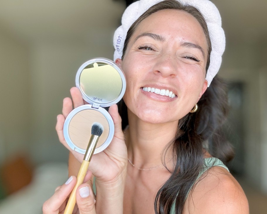 woman in headband holding pressed powder and brush