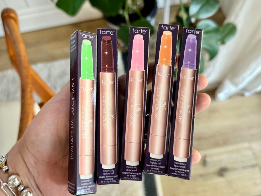 hand holding 5 different tarte lip plumping glosses