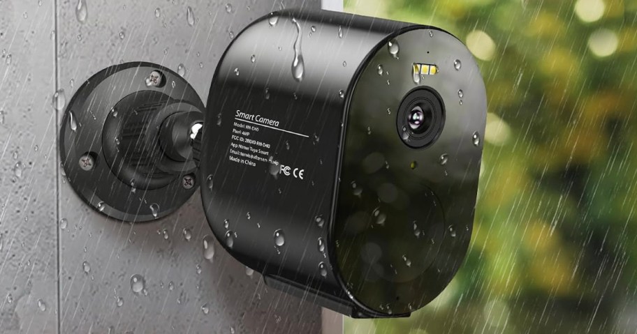 black security camera hanging on wall while its raining 