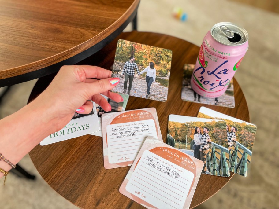woman holding a Walgreens custom photo coaster above an assortment of coasters and a pink La Croix can