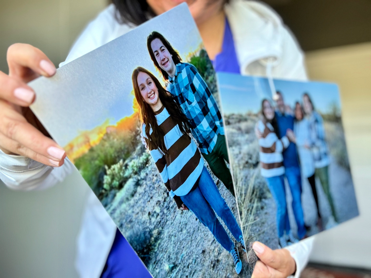 woman holding up 2 walgreens metal prints featuring images of teenagers