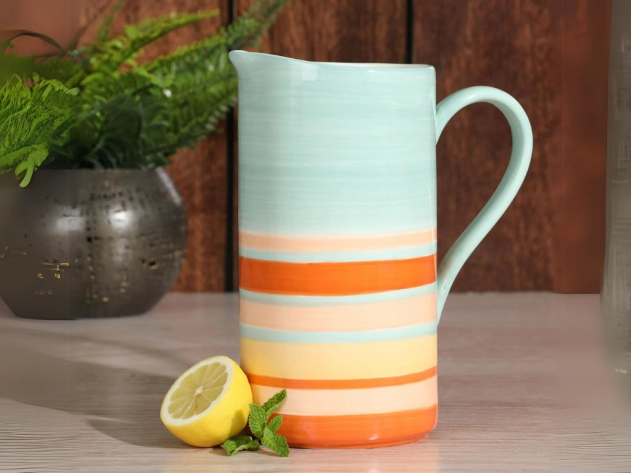 orange, white and blue striped pitcher next to half a lemon on a counter