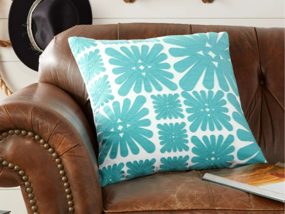 retro style teal blue and white floral pillow on a leather couch