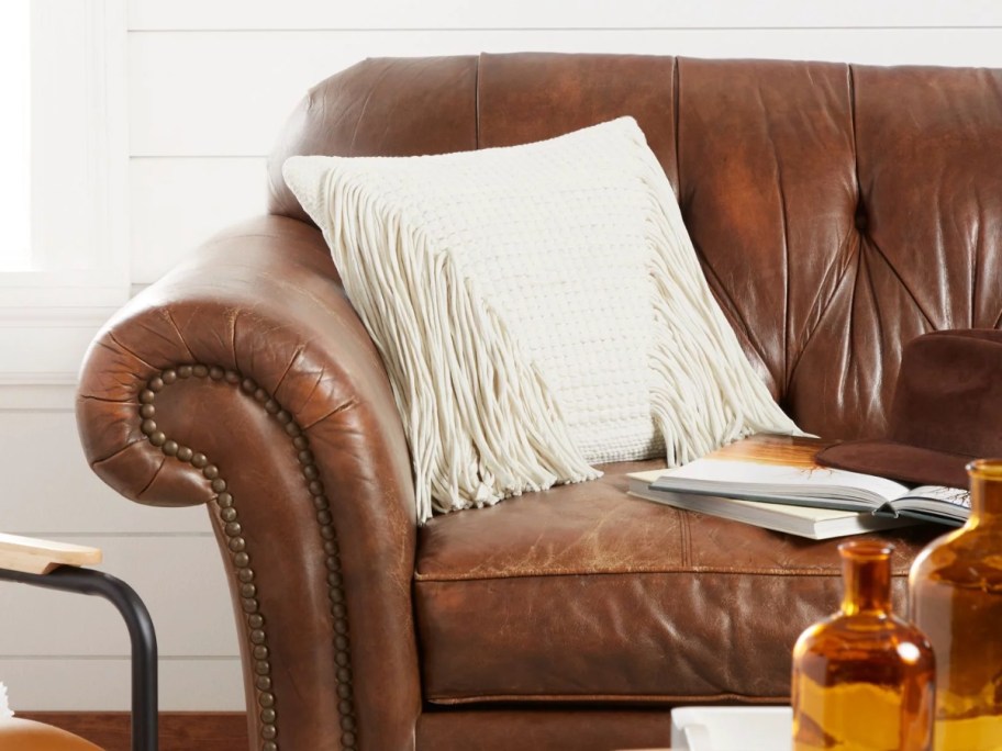 white pillow with fringe on a leather couch