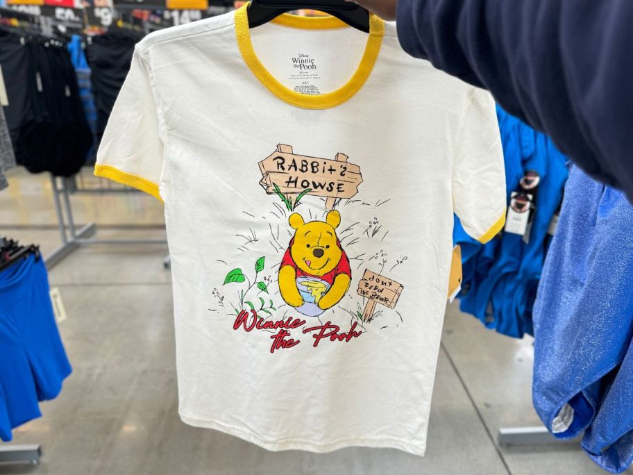 a womans hand holding a winnie the pooh tee