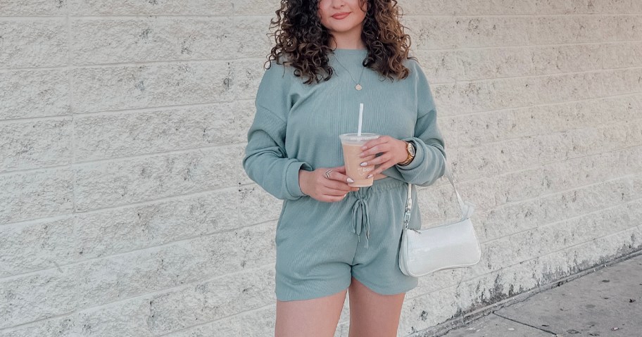 woman wearing teal lounge set holding coffee and purse