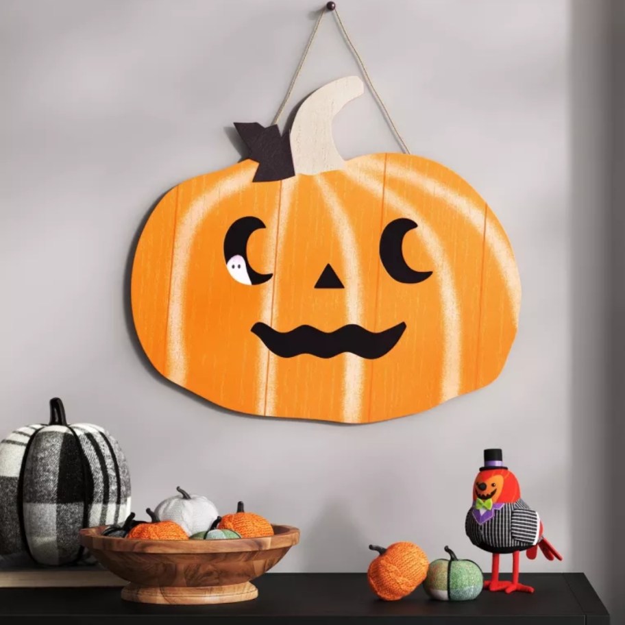 large Halloween Jacko-lantern wood sign hanging on a wall above other decor