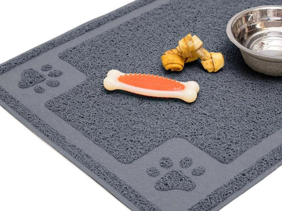 grey pet food mat with paw prints, dog treats and metal water bowl
