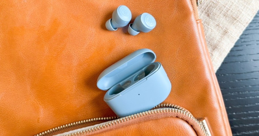 light blue earbuds with charging case on a brownish orange backpack bag