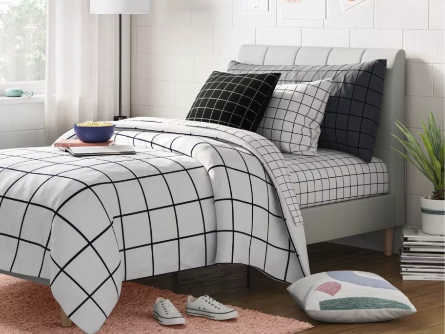 platform bed with a grey headboard and black and white checkered bedspread and sheets