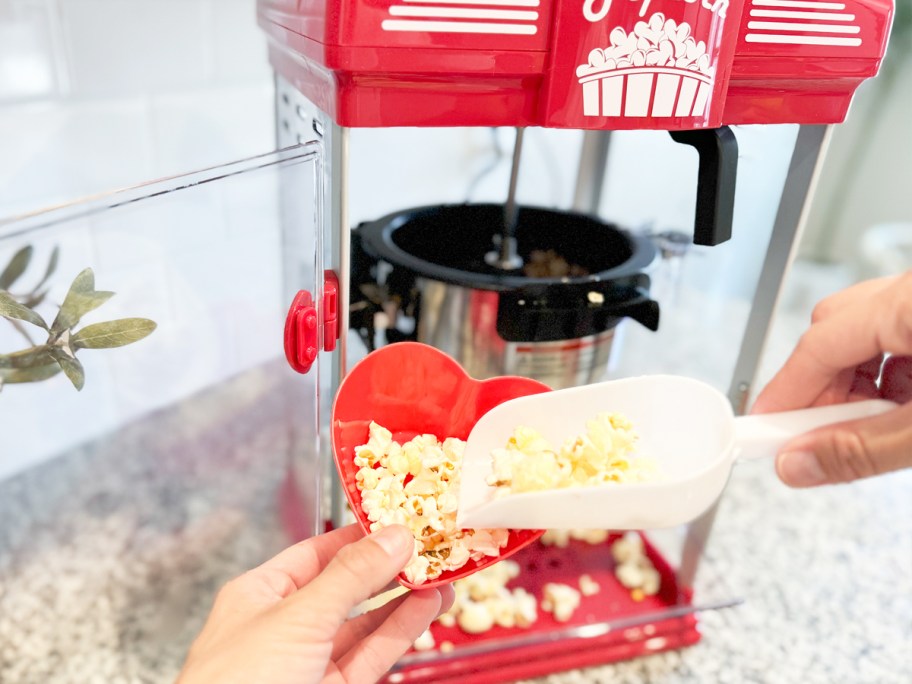 scooping popcorn into red heart-shaped bowl