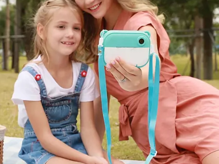 mom and little girl taking a selfie pic with a kid's blue and white digital camera