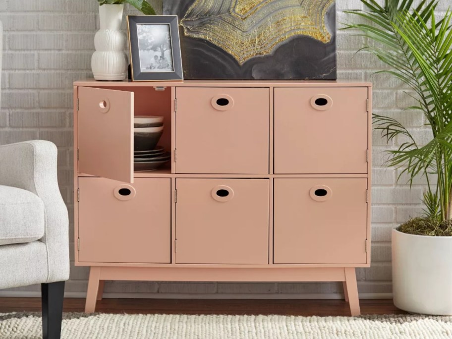 pink storage cabinet with 6 cubbies and doors in a living room 