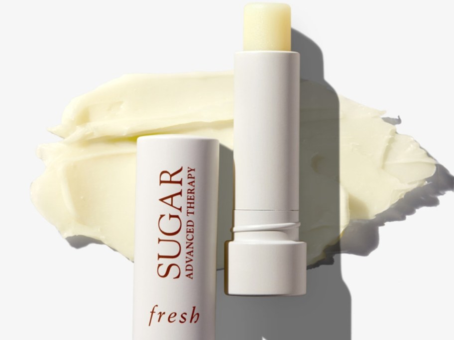 open tube of fresh Sugar Advanced Therapy Treatment Lip Balm laying on top of spread out balm