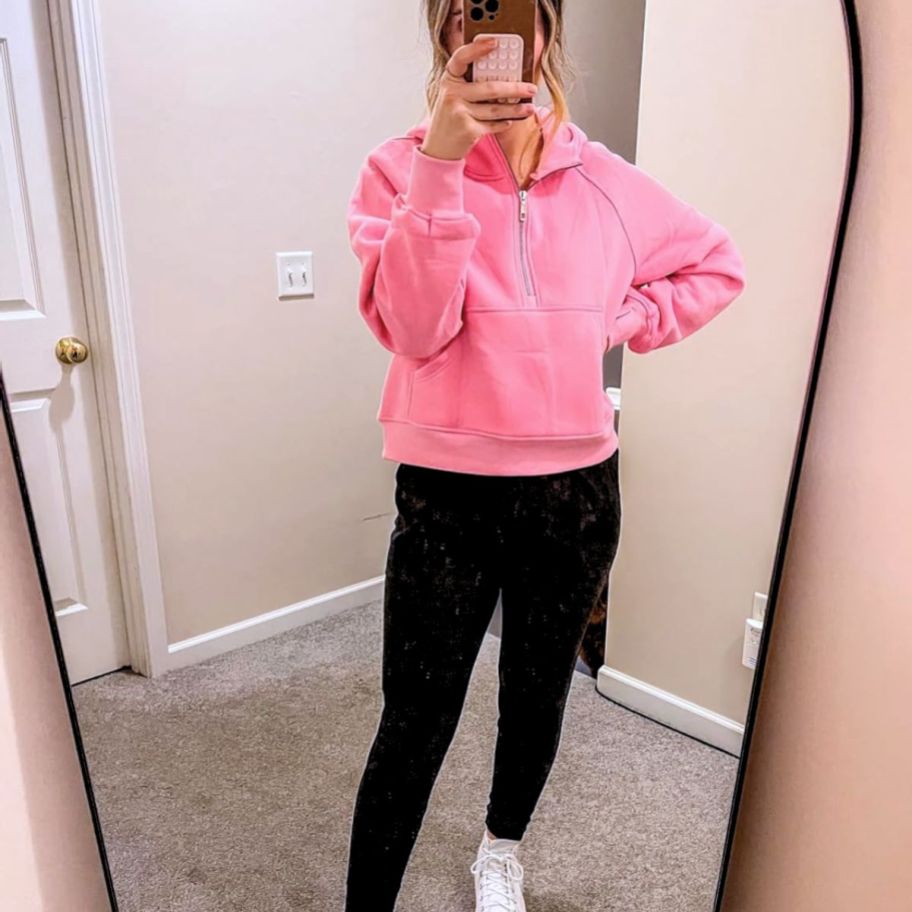 a woman taking a selfies and wearing pink cropped half zip hoodie
