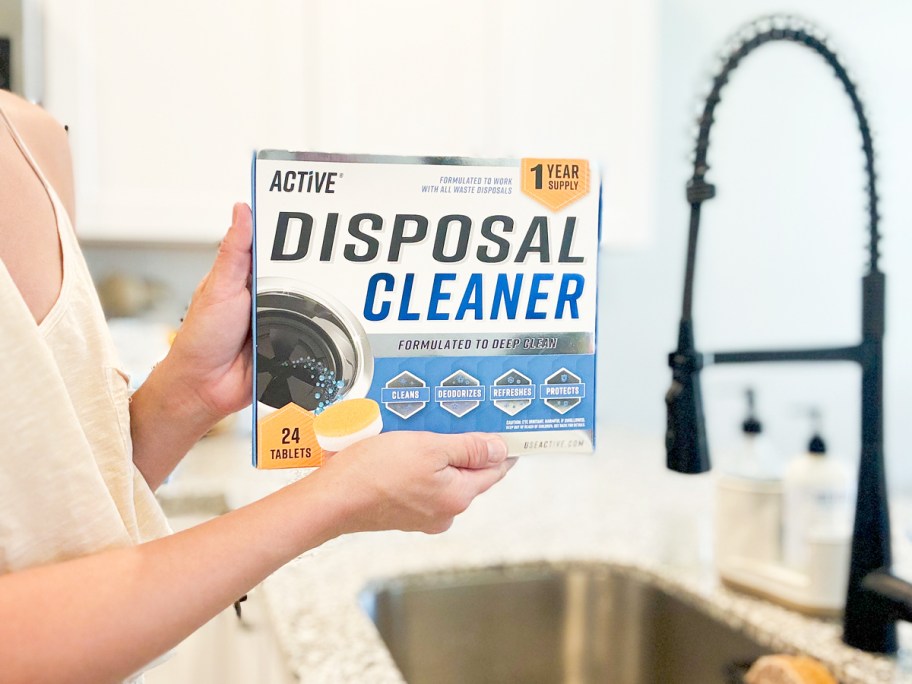 holding a box of Active Garbage Disposal Cleaner over kitchen sink