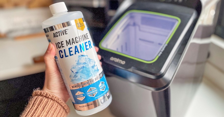 hand holding up a bottle of Active Ice Machine Cleaner next to countertop ice machine