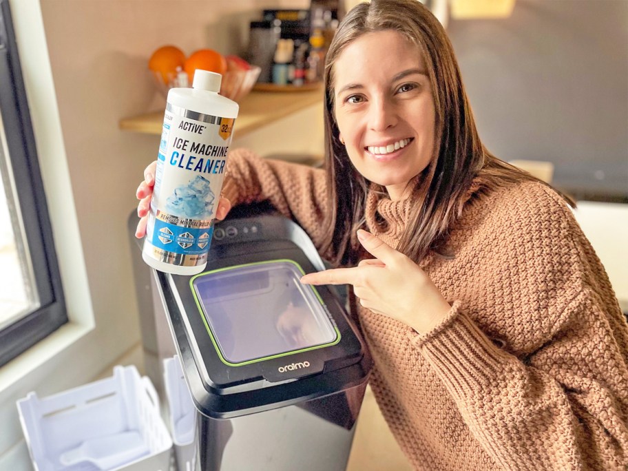 woman holding up and pointing to a bottle of Active Ice Machine Cleaner