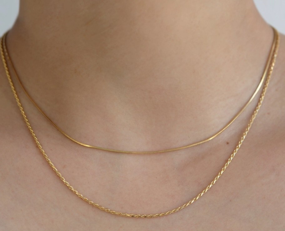 close up of woman wearing gold chain necklaces 