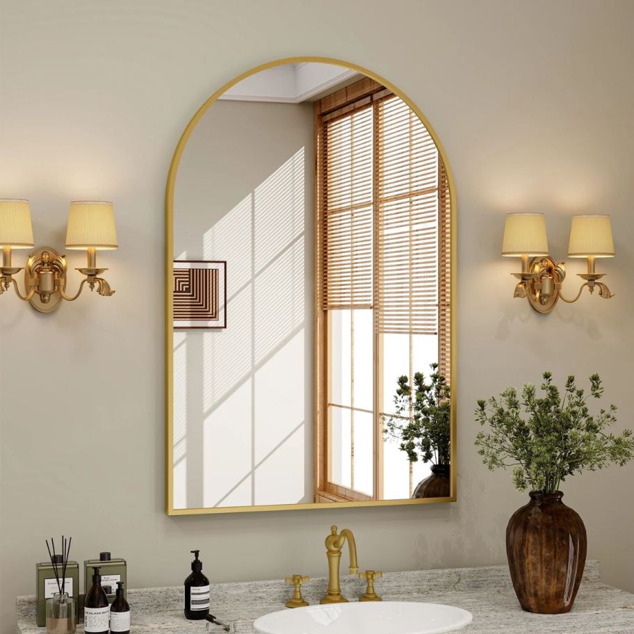 arched wall mirror above a bathroom sink