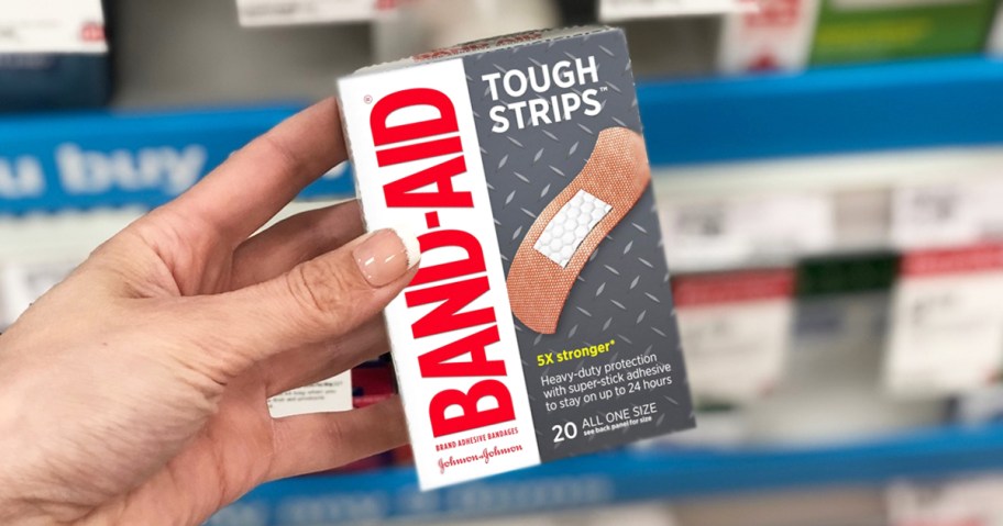 hand holding a box of Band-Aid Tough Strips Bandages