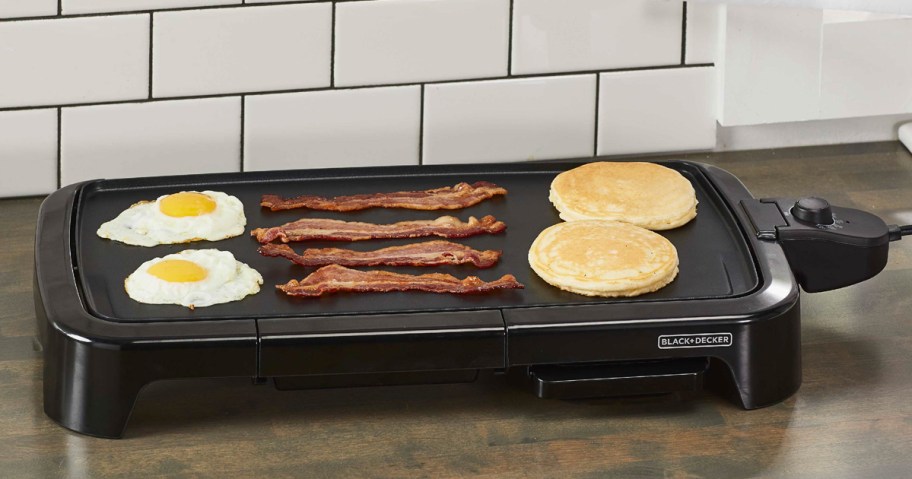 eggs, bacon, and pancakes cooking on electric griddle