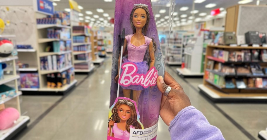 hand holding a Blind Barbie Doll in the box in a store aisle