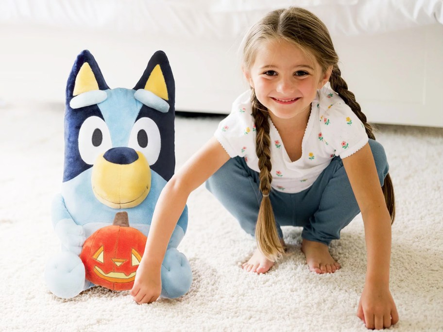 girl next to a bluey halloween plush