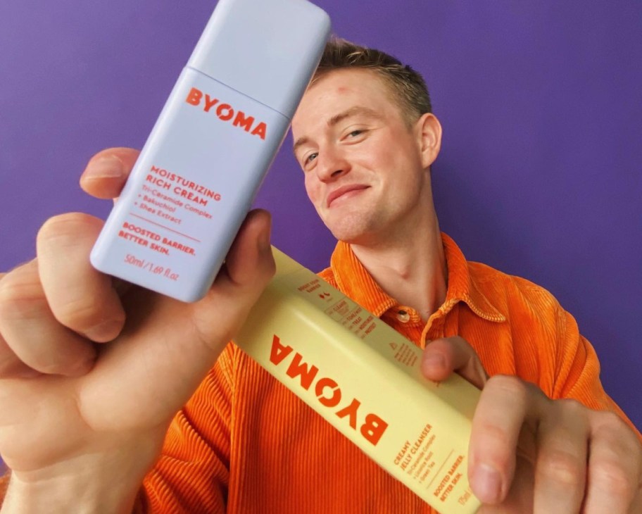 guy holding skincare in front of face