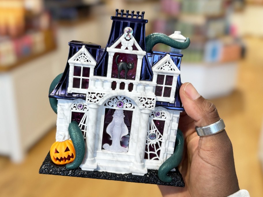 hand holding up a haunted house figurine
