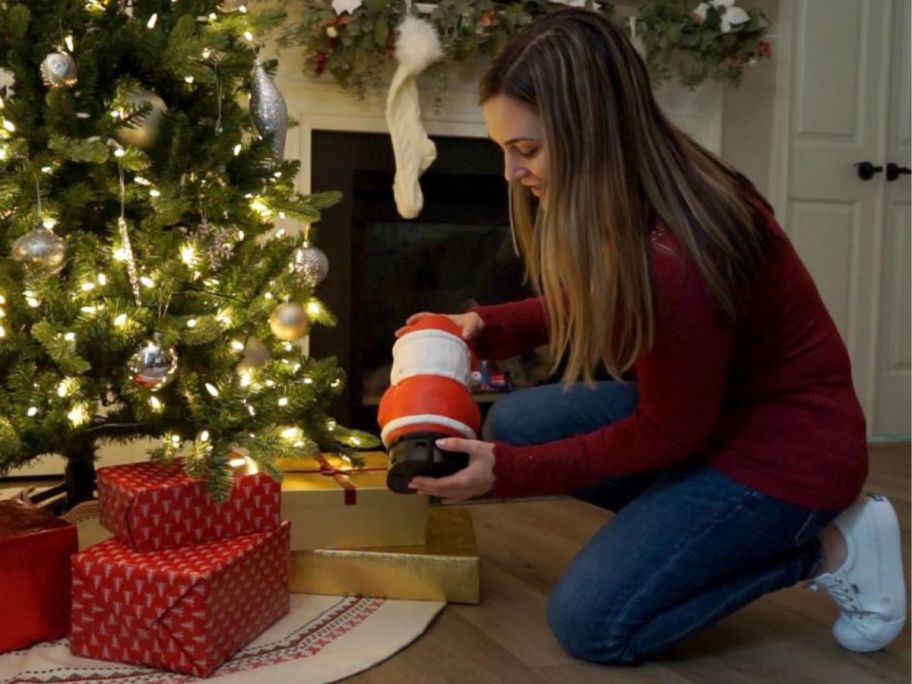Woman placing a Cinemates Christmas Decoration Santa under a tree