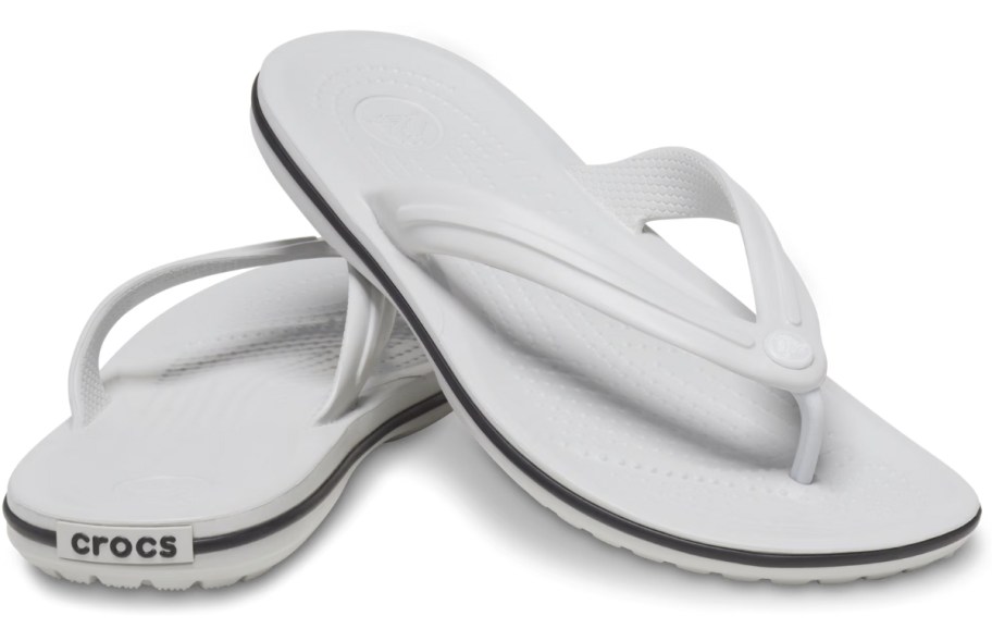 pair of white Crocs flip flips with a blue stripe around the sole