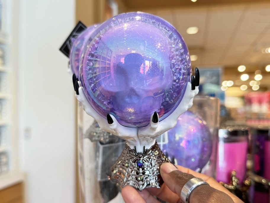 hand holding up a purple crystal ball