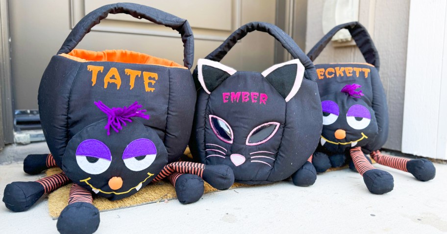 three spider and cat personalized halloween treat baskets sitting at front door