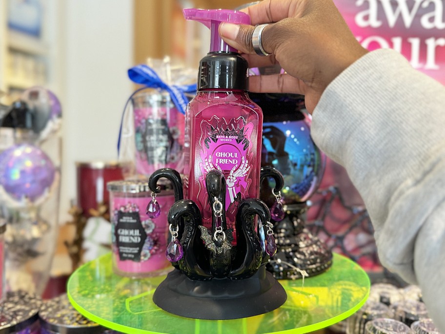 hand grabbing a pink hand soap from halloween soap holder