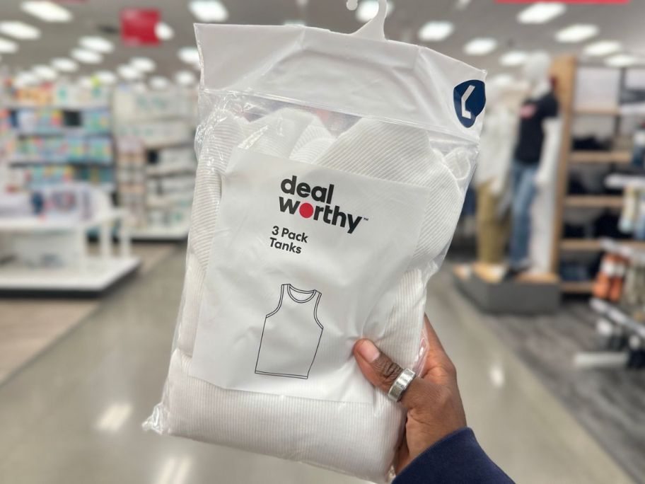 Hand holding up a pack of Dealworthy Men's Tank Tops at Target