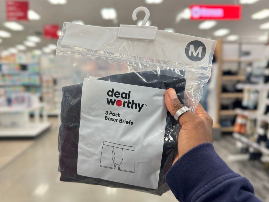 Hand holding up a pack of Dealworthy Men's Boxer Briefs at Target